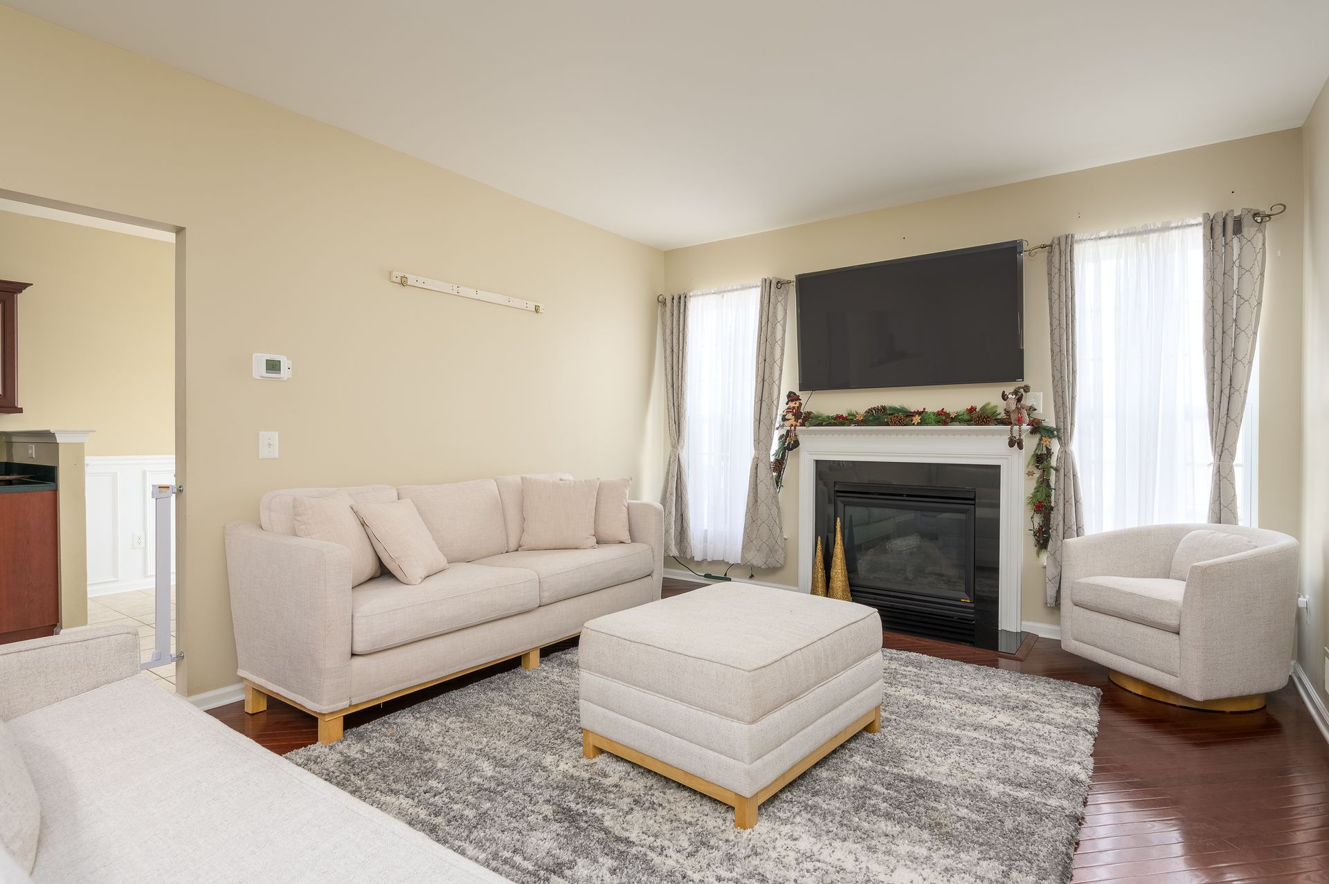 A living room with a couch , chair , ottoman , fireplace and television.