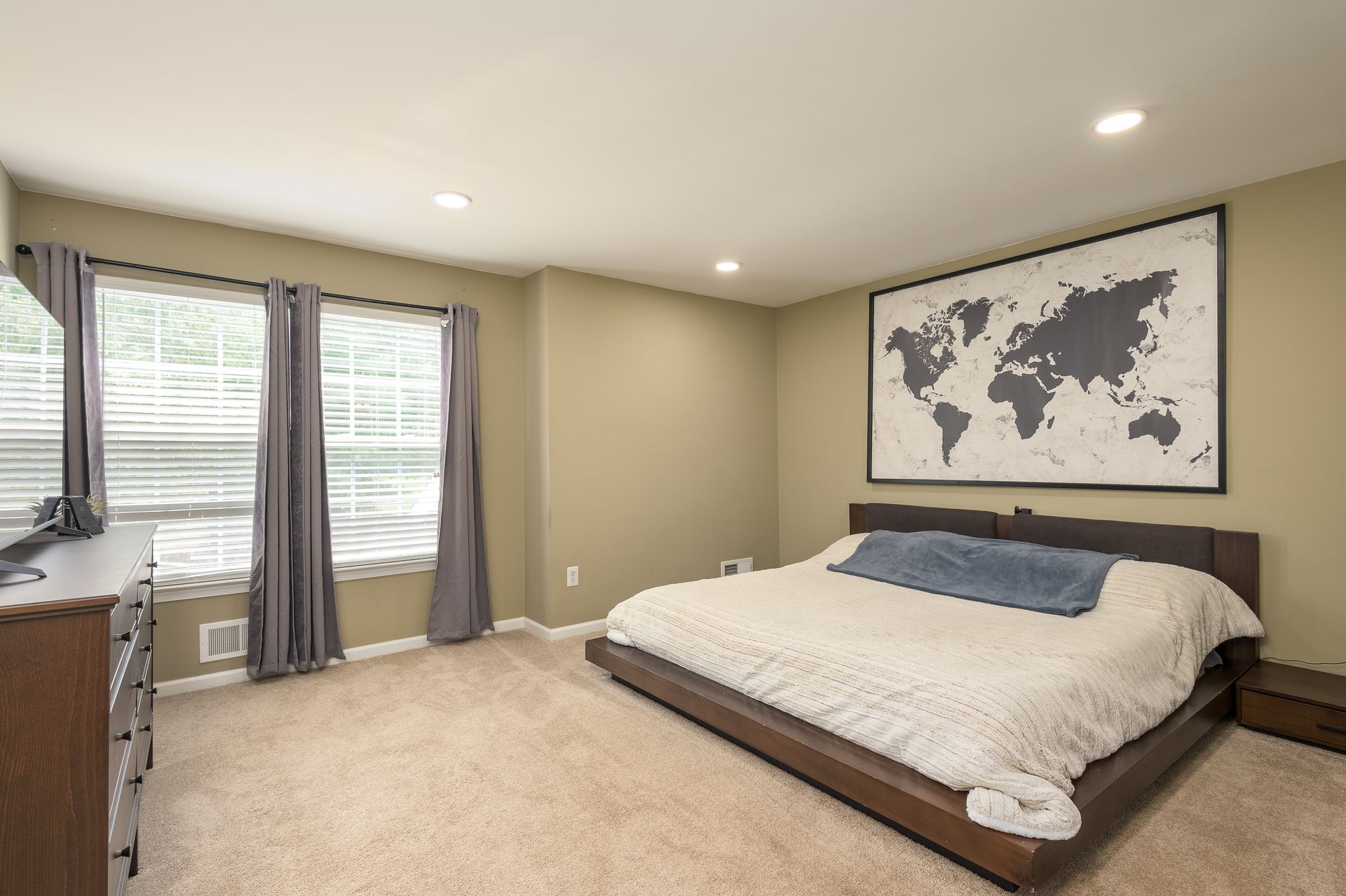 A bedroom with a large bed and a map of the world on the wall.