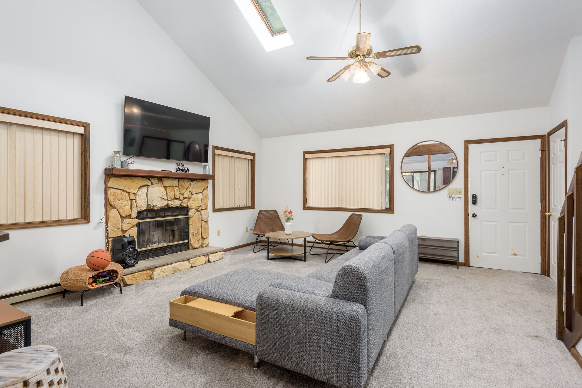 A living room with a couch , fireplace , television and ceiling fan.