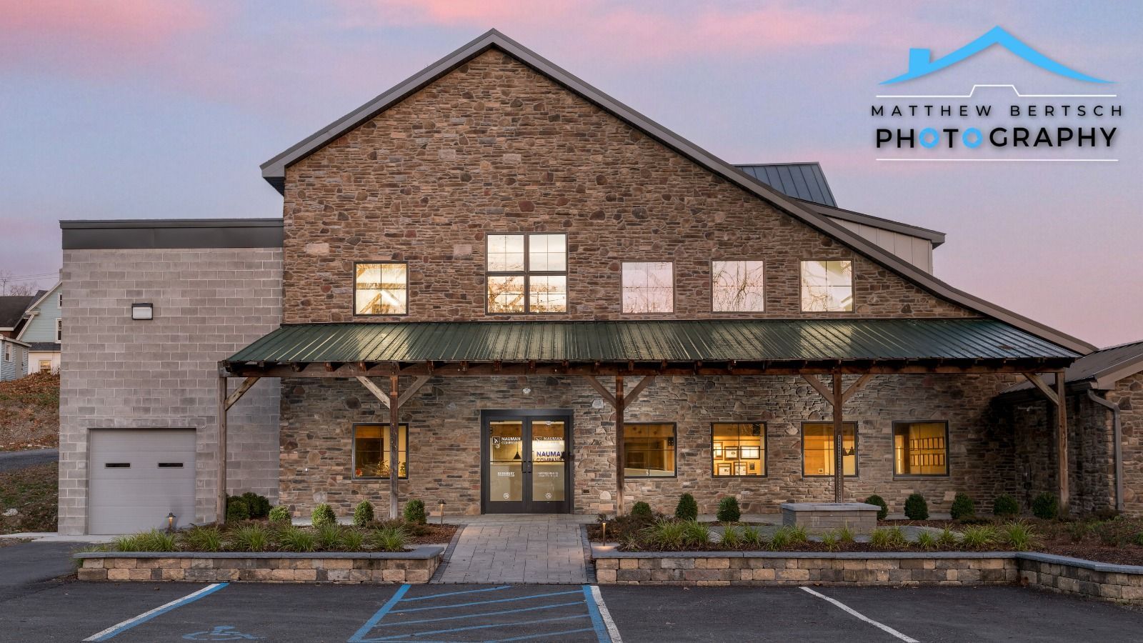 A large brick building with a green awning and a parking lot in front of it.