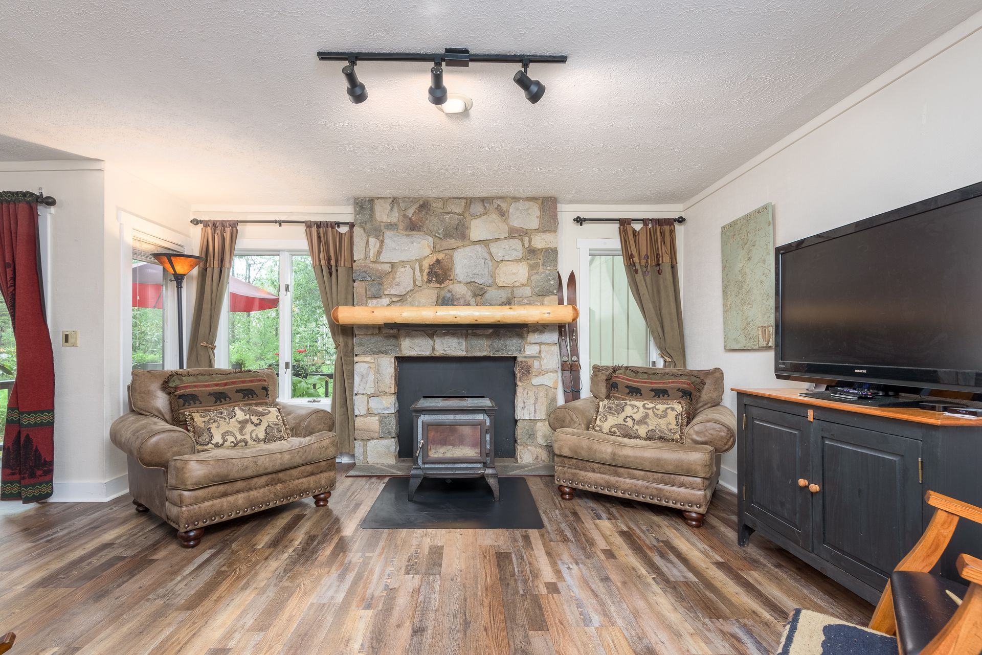 A living room with a fireplace , chairs , and a flat screen tv.