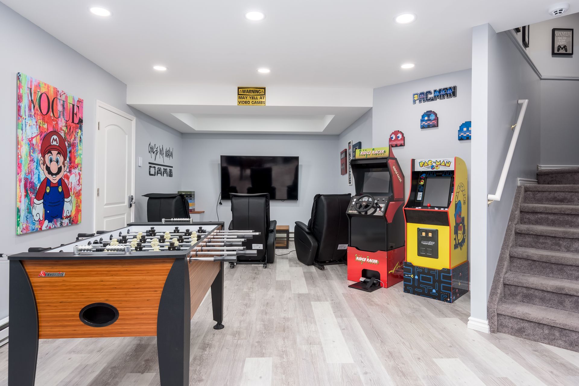 A game room with a table , arcade machines , and a television.