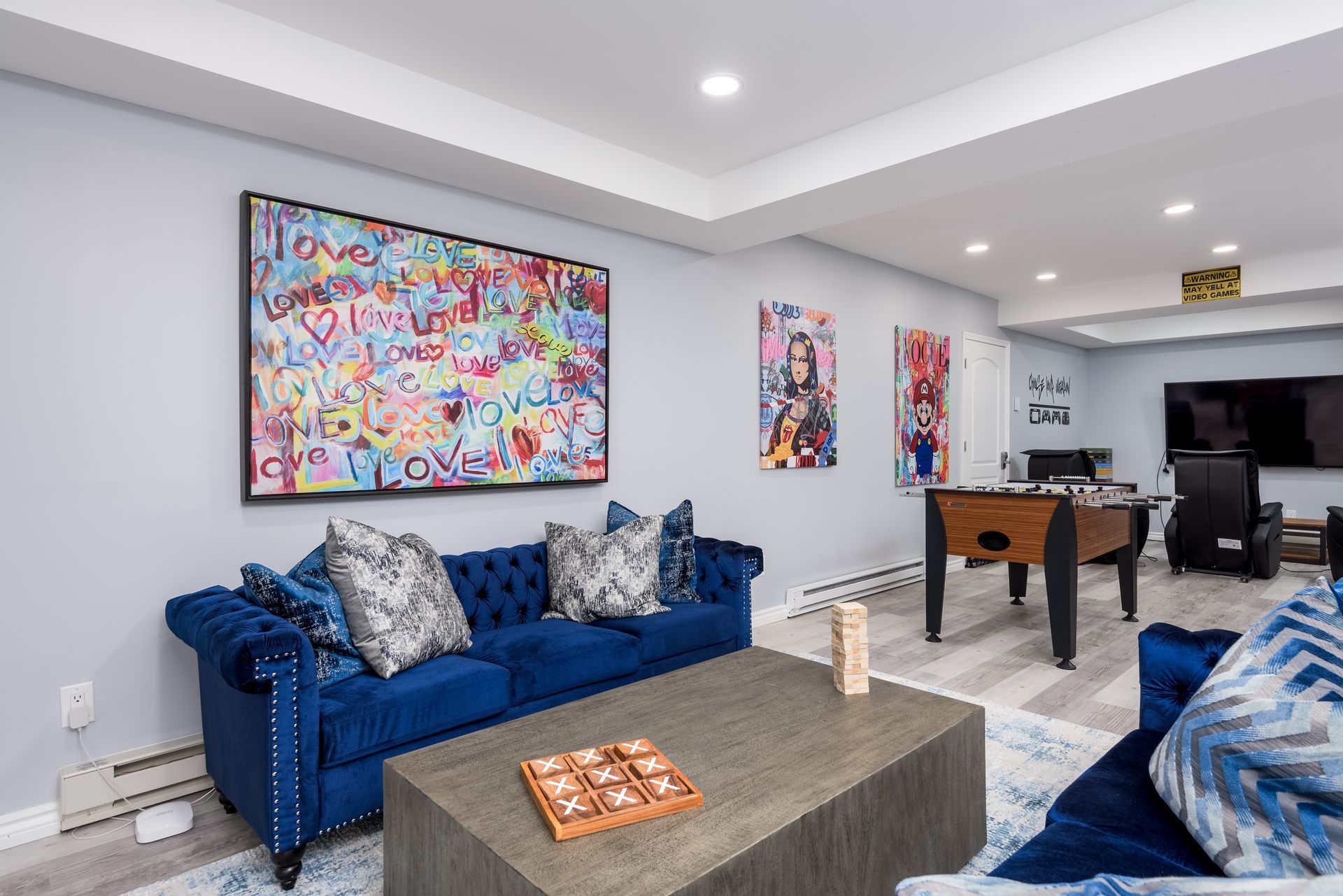 A living room with a blue couch , table , and pool table.