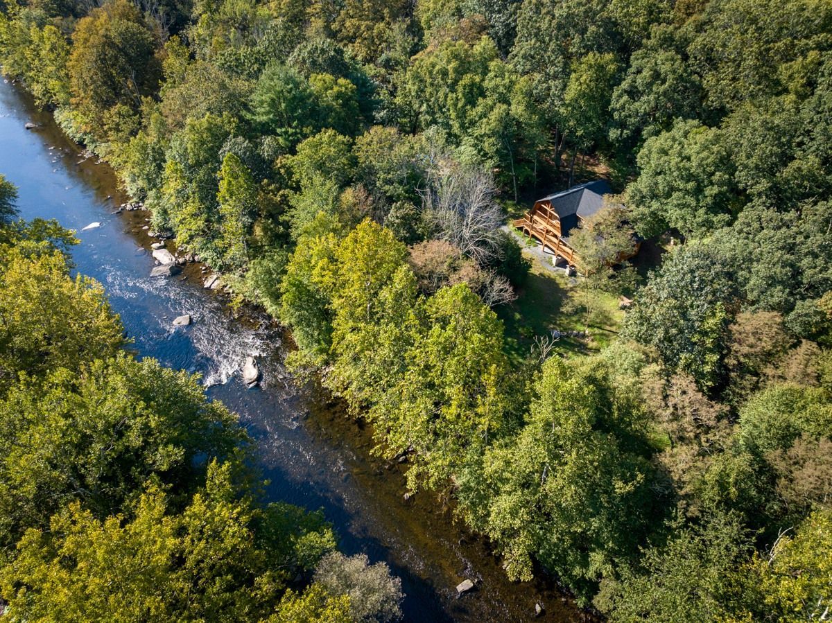 An aerial view of a river surrounded by trees and a house.