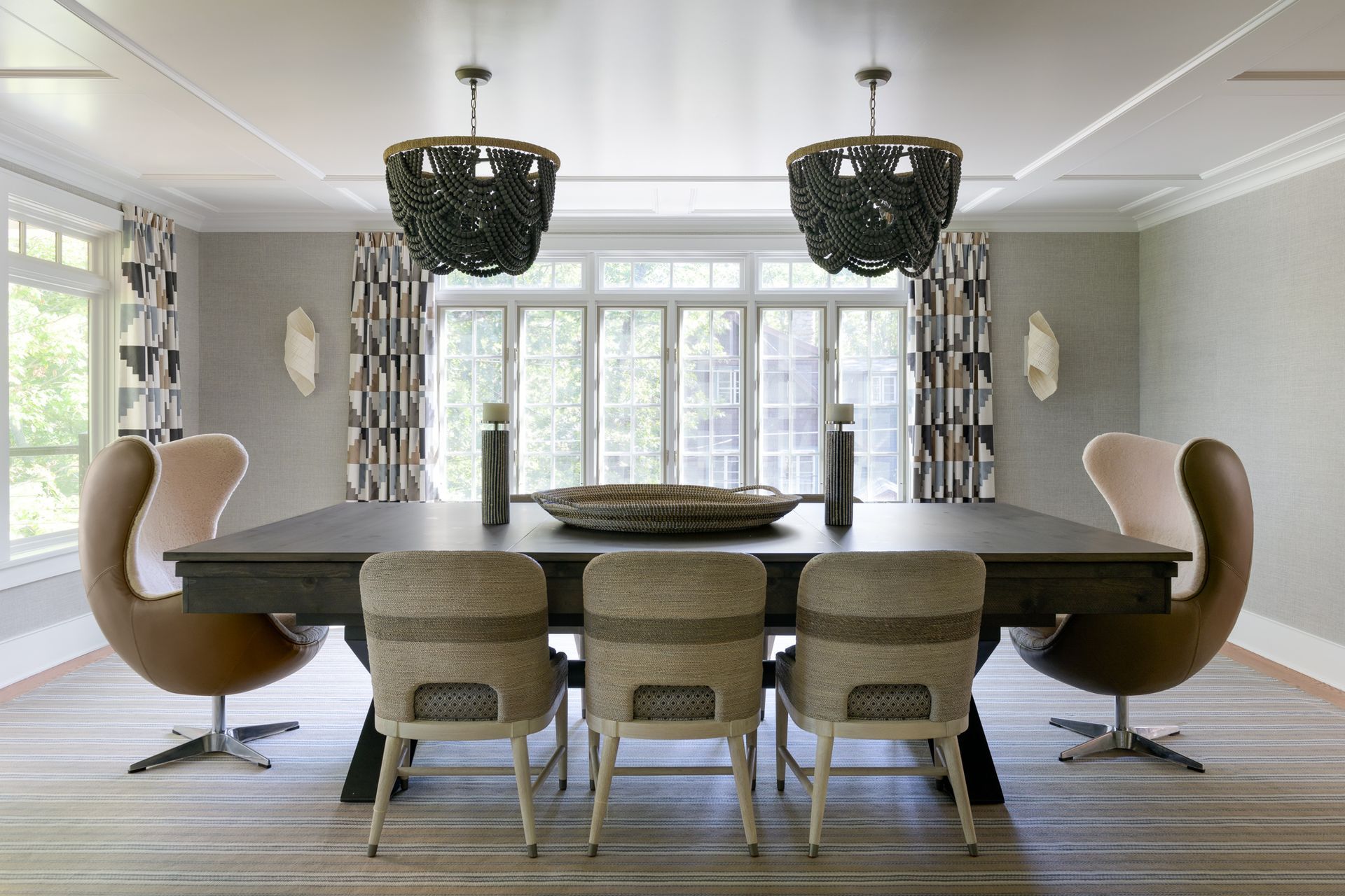 A dining room with a table and chairs and two chandeliers hanging from the ceiling.