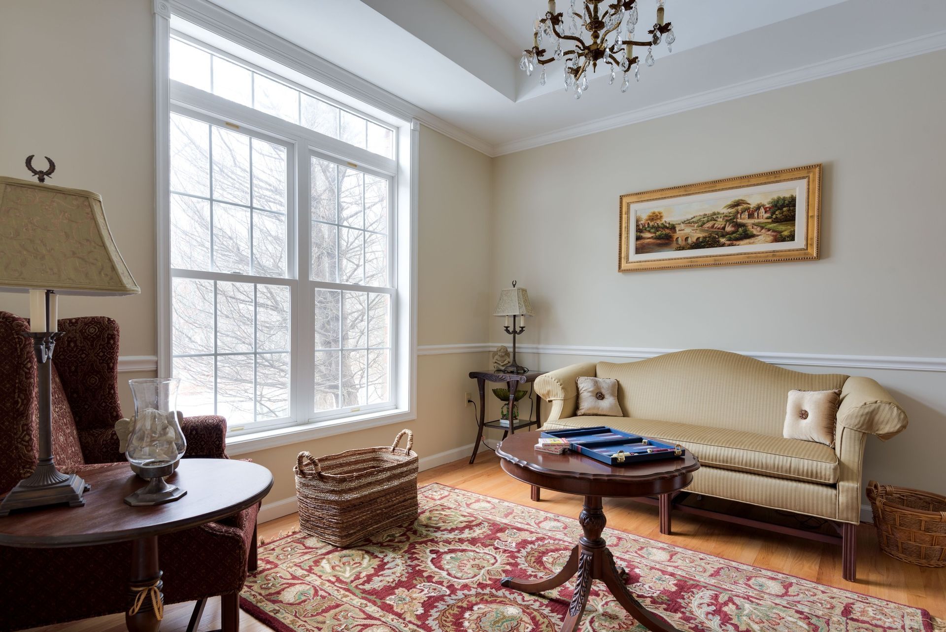 A living room with a couch , chairs , a table and a picture on the wall.
