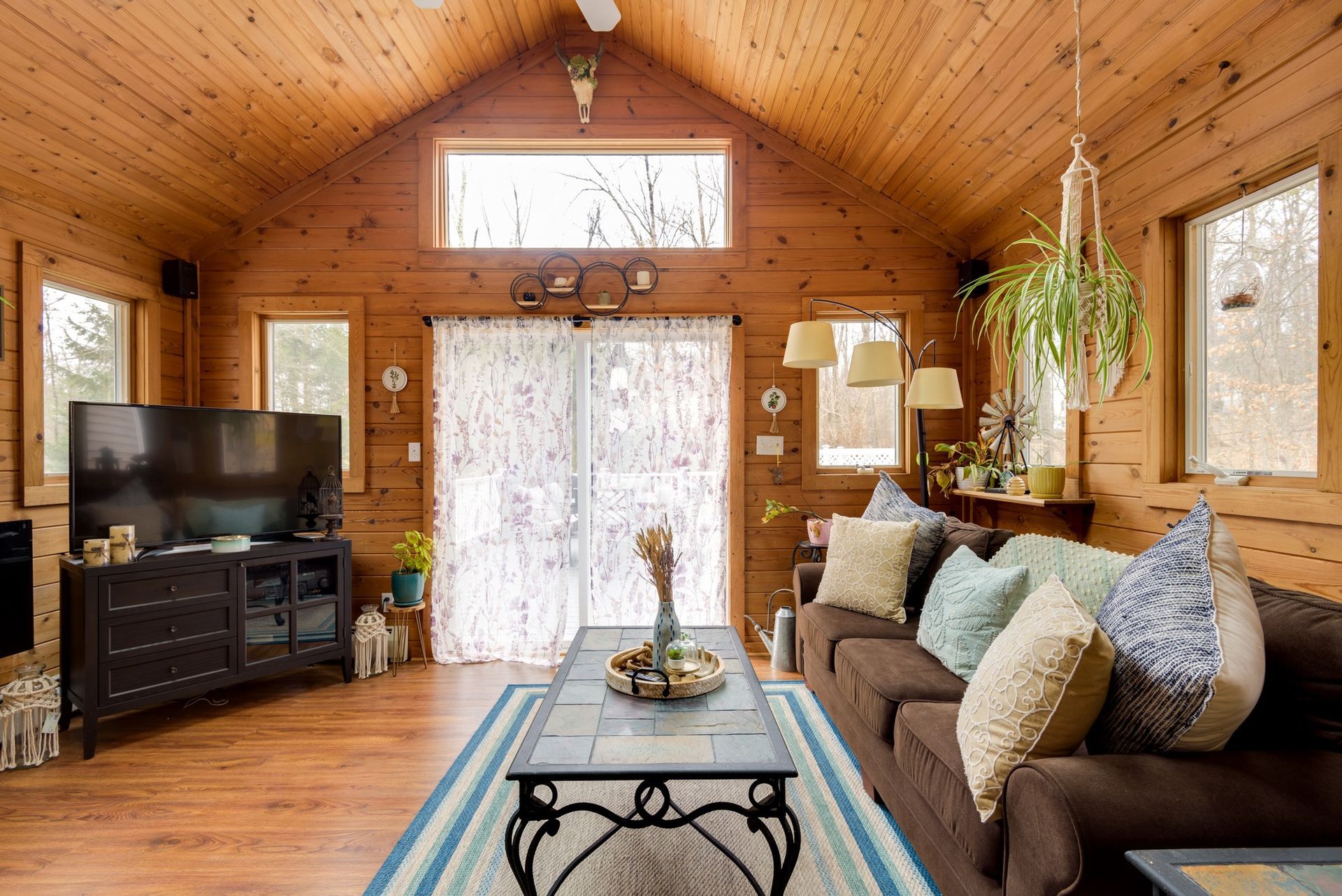 A living room in a log cabin with a couch , coffee table and television.