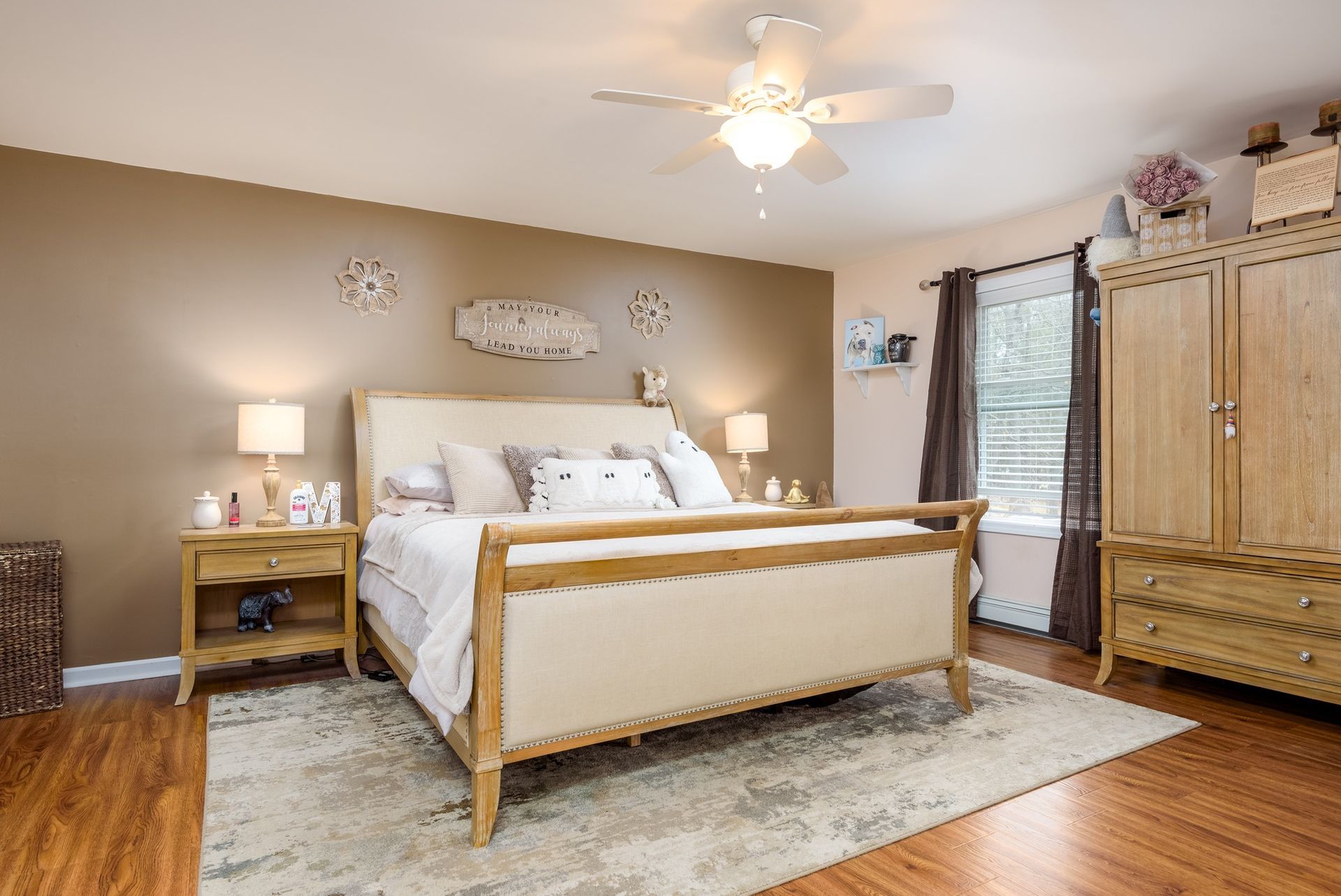 A bedroom with a bed , nightstands , cabinets and a ceiling fan.