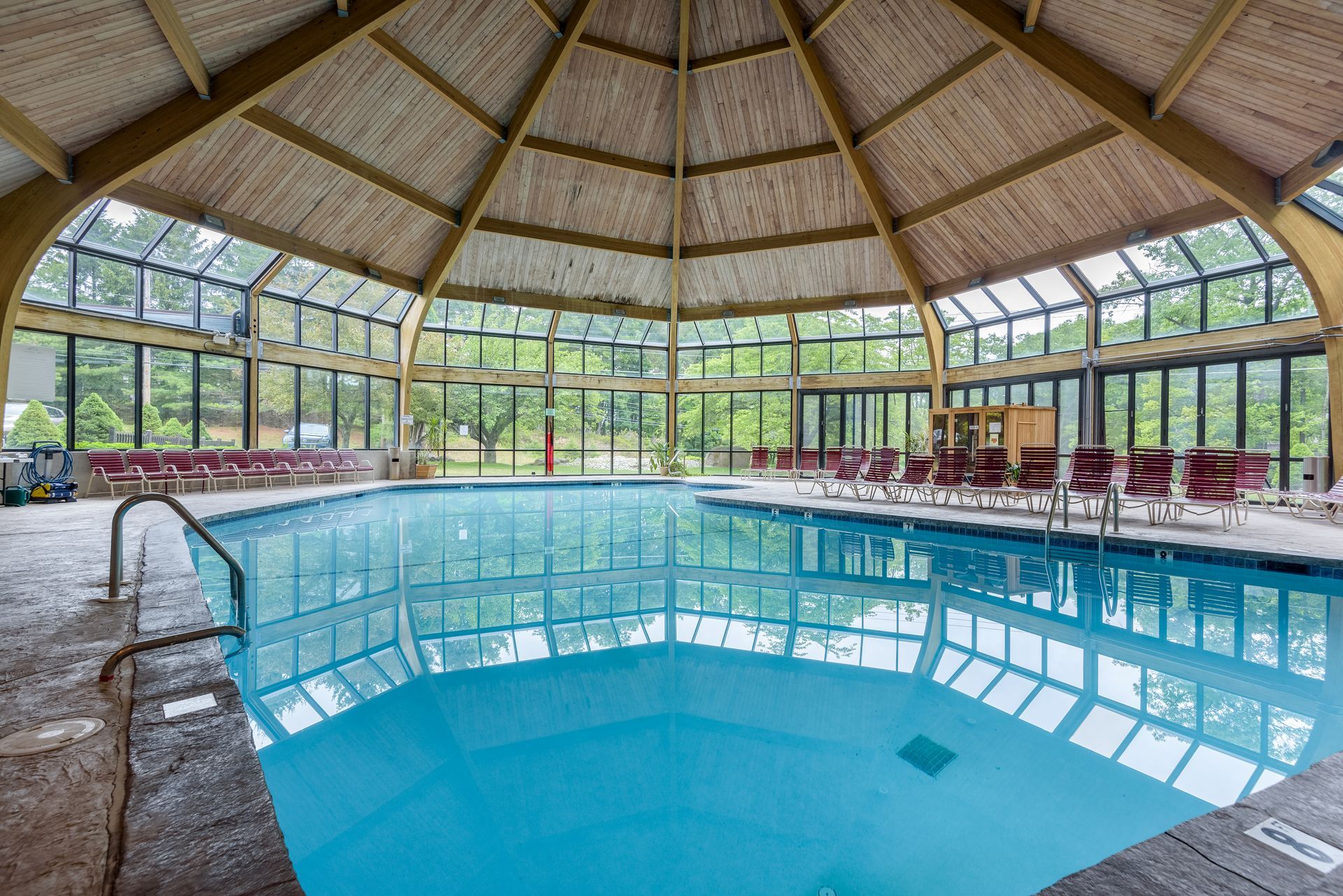 A large indoor swimming pool with a wooden roof and lots of windows.