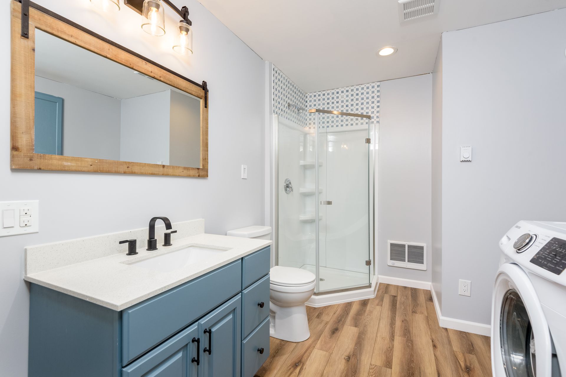 A bathroom with a sink , toilet , shower and washer and dryer.