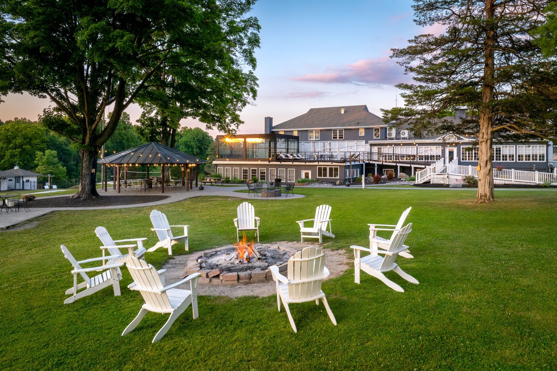 A group of chairs are sitting around a fire pit in a grassy field.