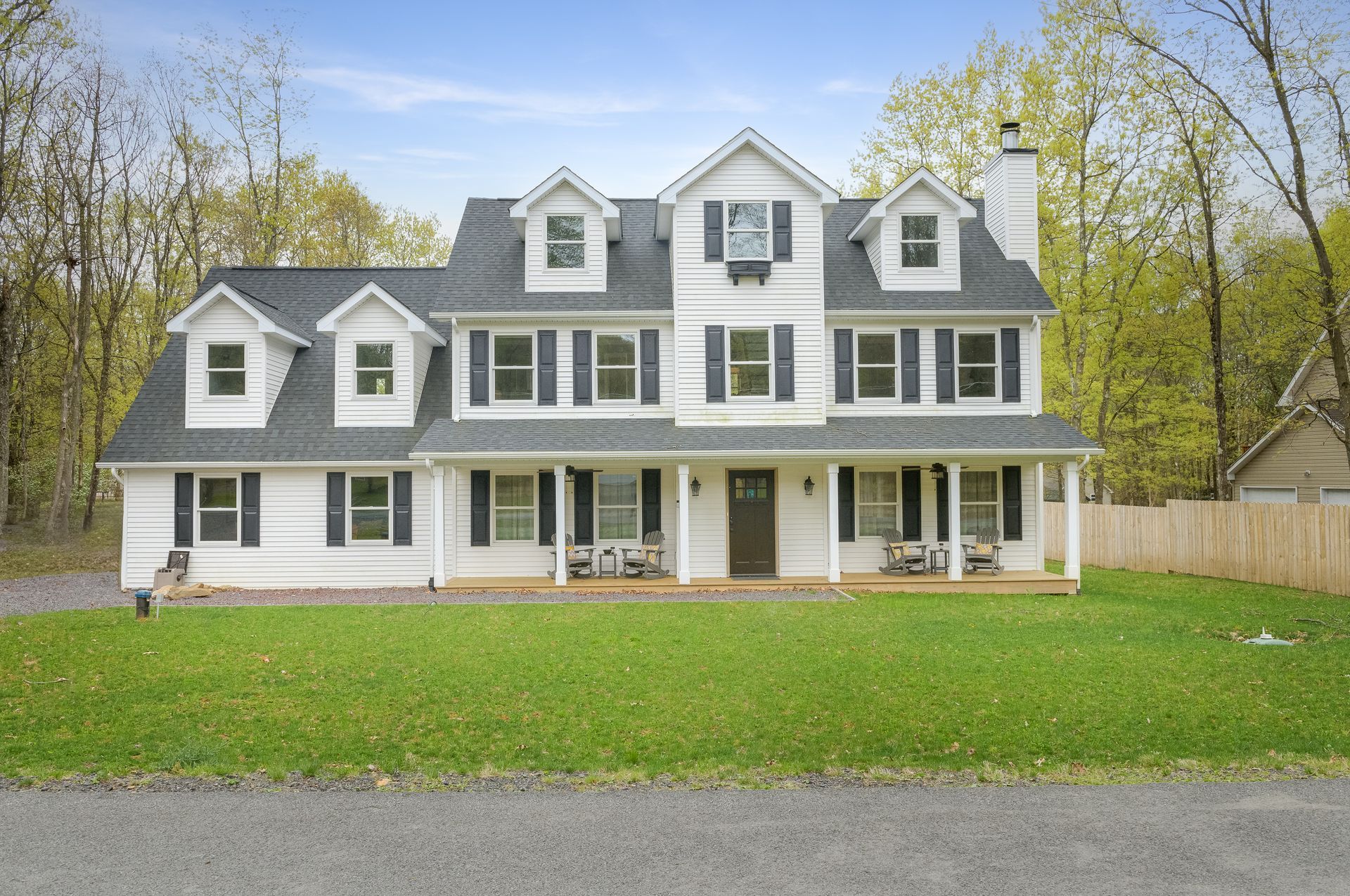 A large white house with a gray roof and black shutters