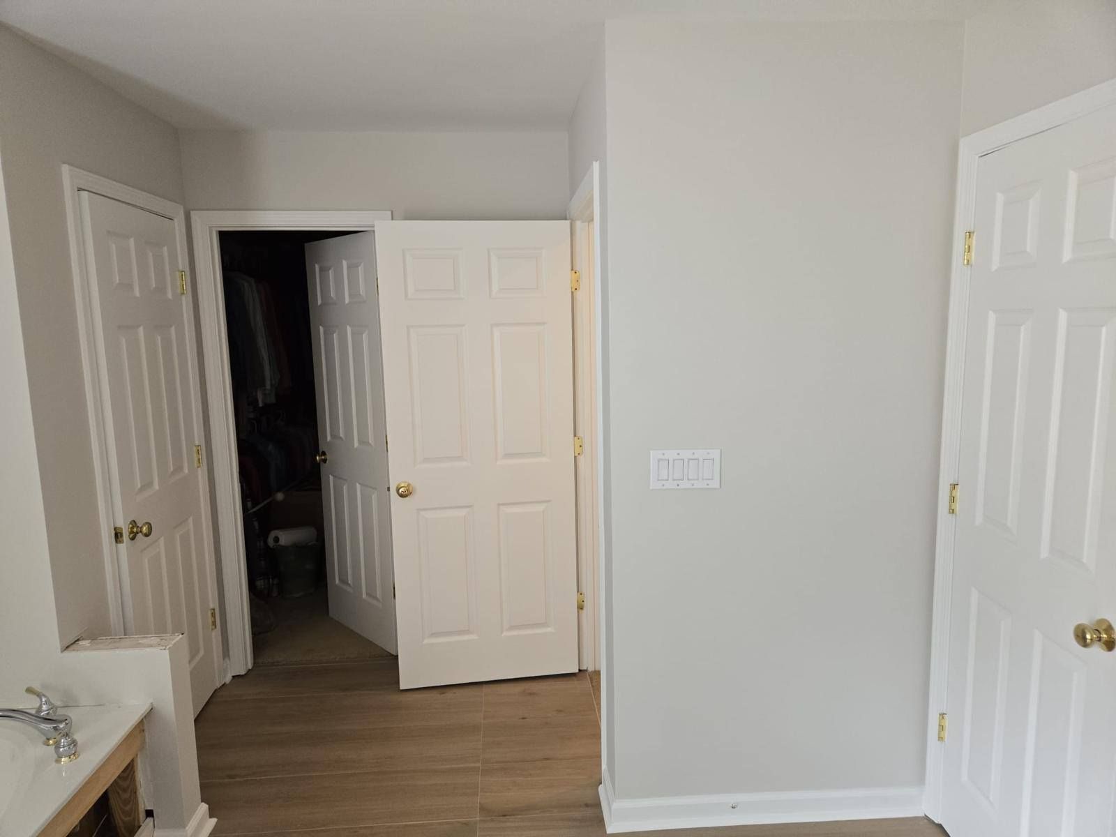 Interior hallway with three white doors, one open to a dark closet, and light-colored walls.