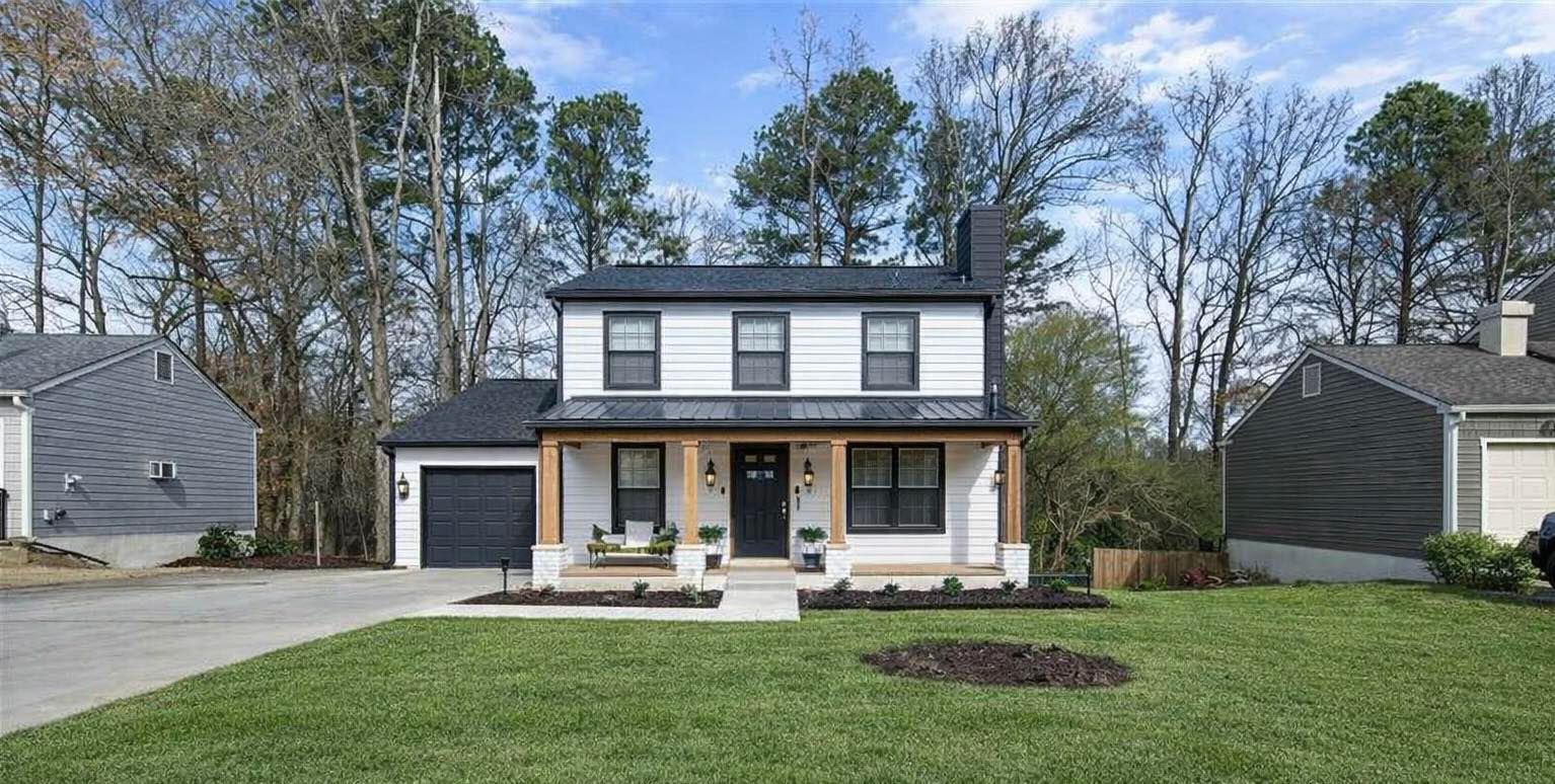 Two-story white house with black trim, porch, and a green lawn.
