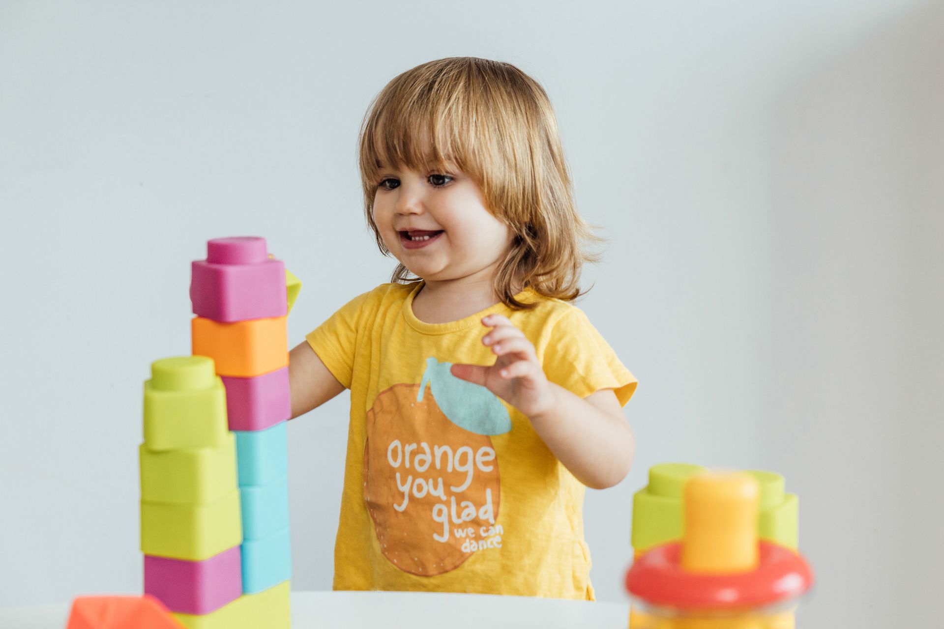 A little girl is playing with toy colored plastic blocks.