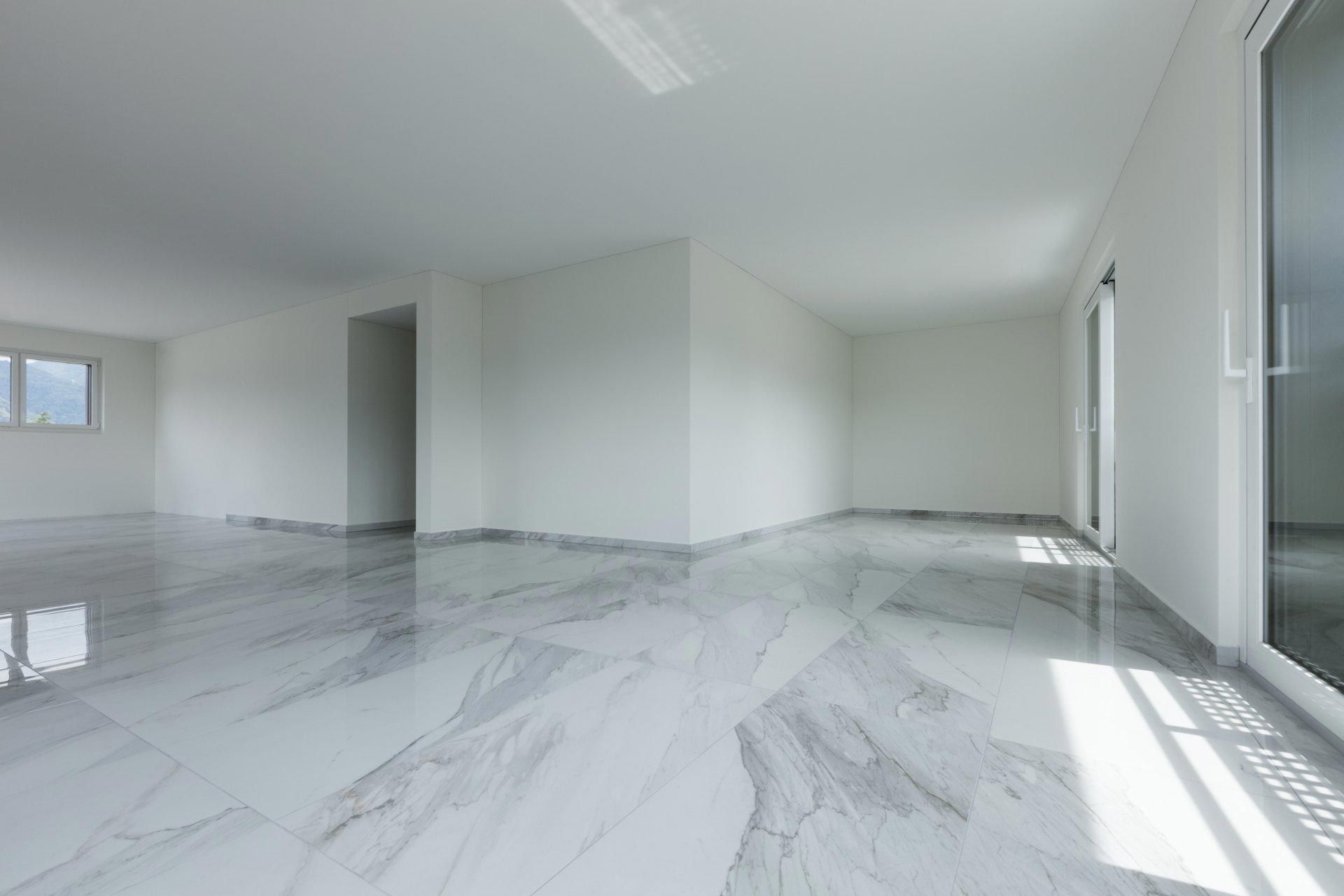 A large empty room with a marble floor and white walls.