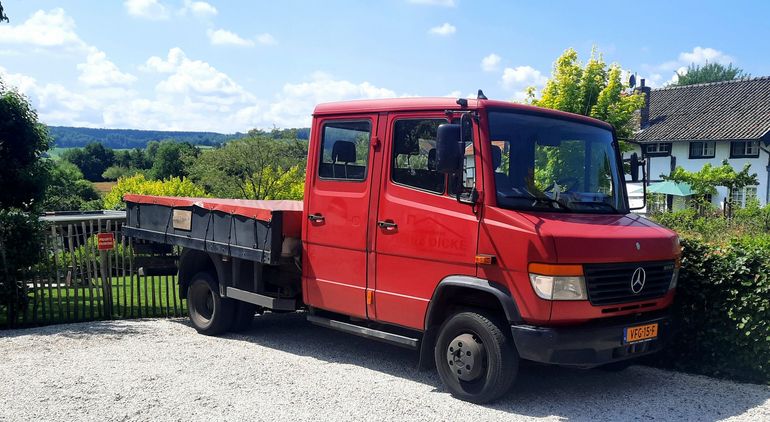 Een rode vrachtwagen voor afvoeren groenafval.