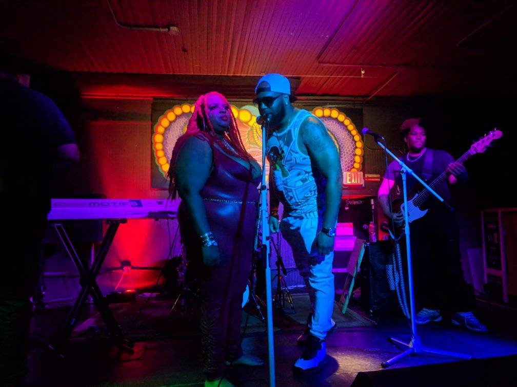 A man and a woman singing into microphones on a stage