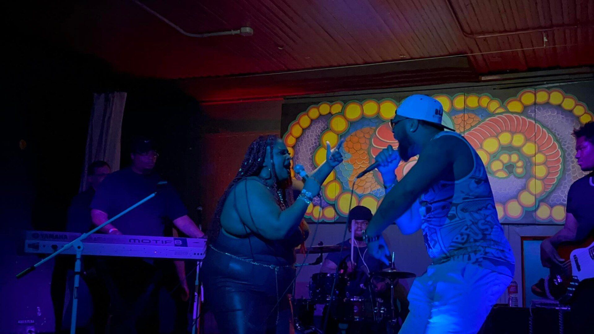 A man and a woman are singing into microphones on a stage.