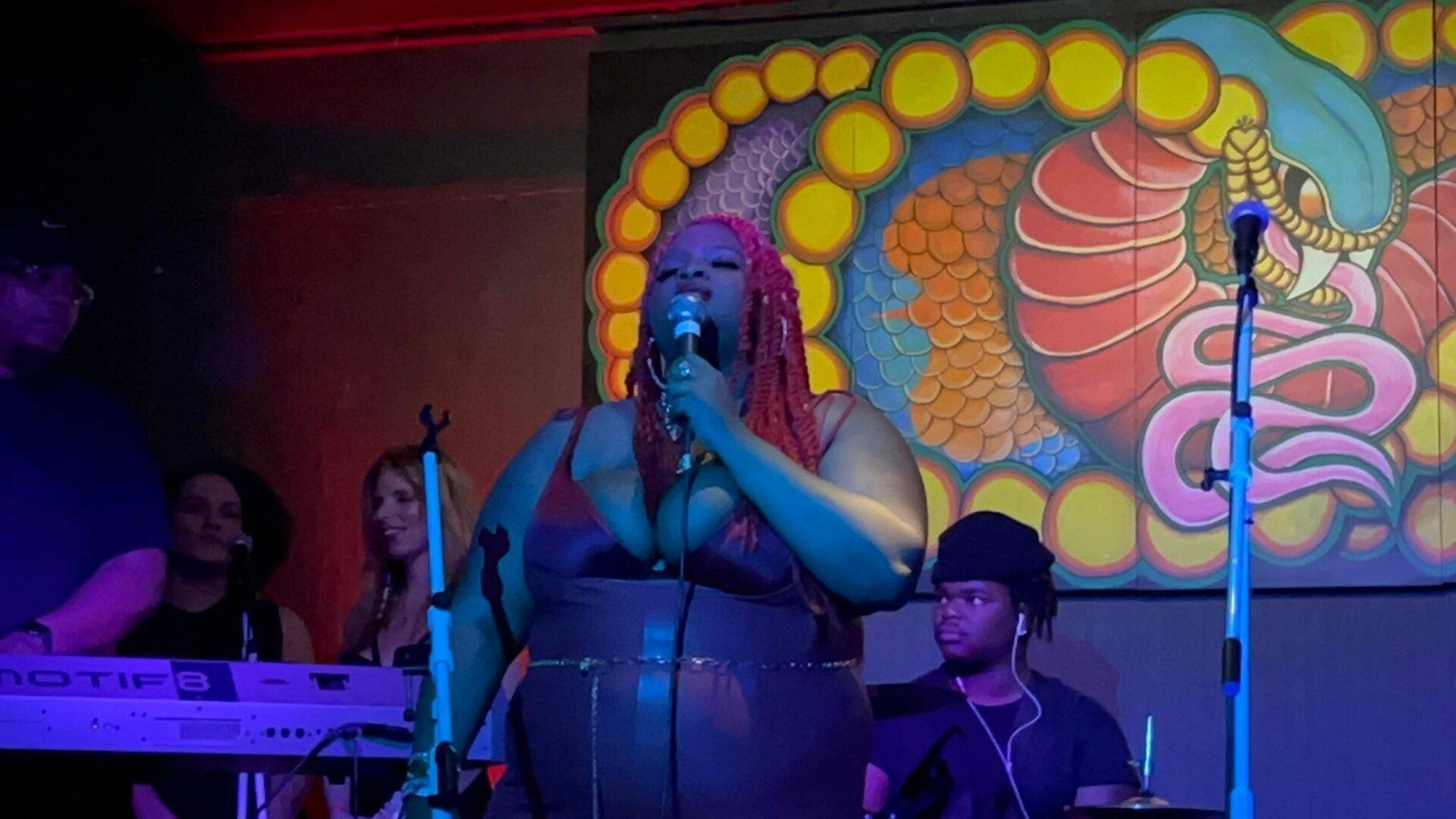 A woman with red hair is singing into a microphone on a stage.