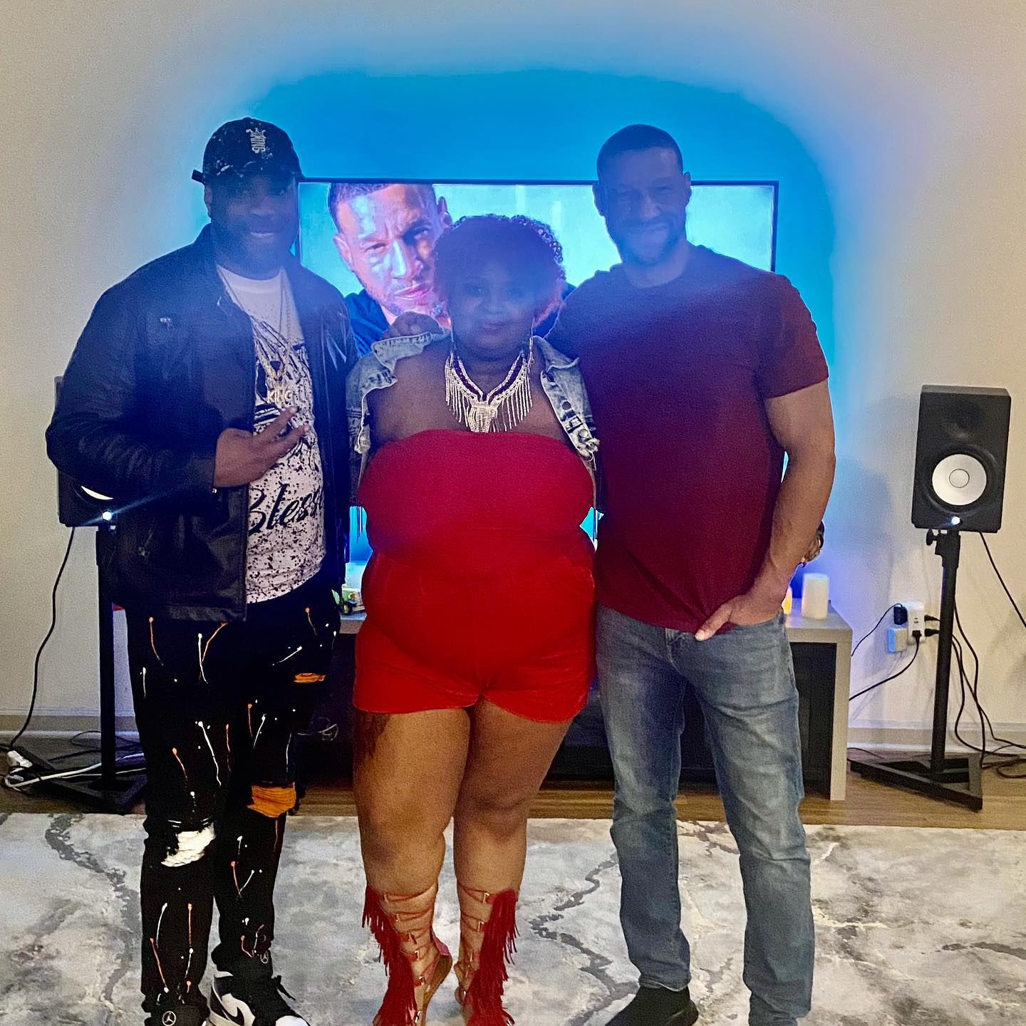 Three people are posing for a picture in front of a television