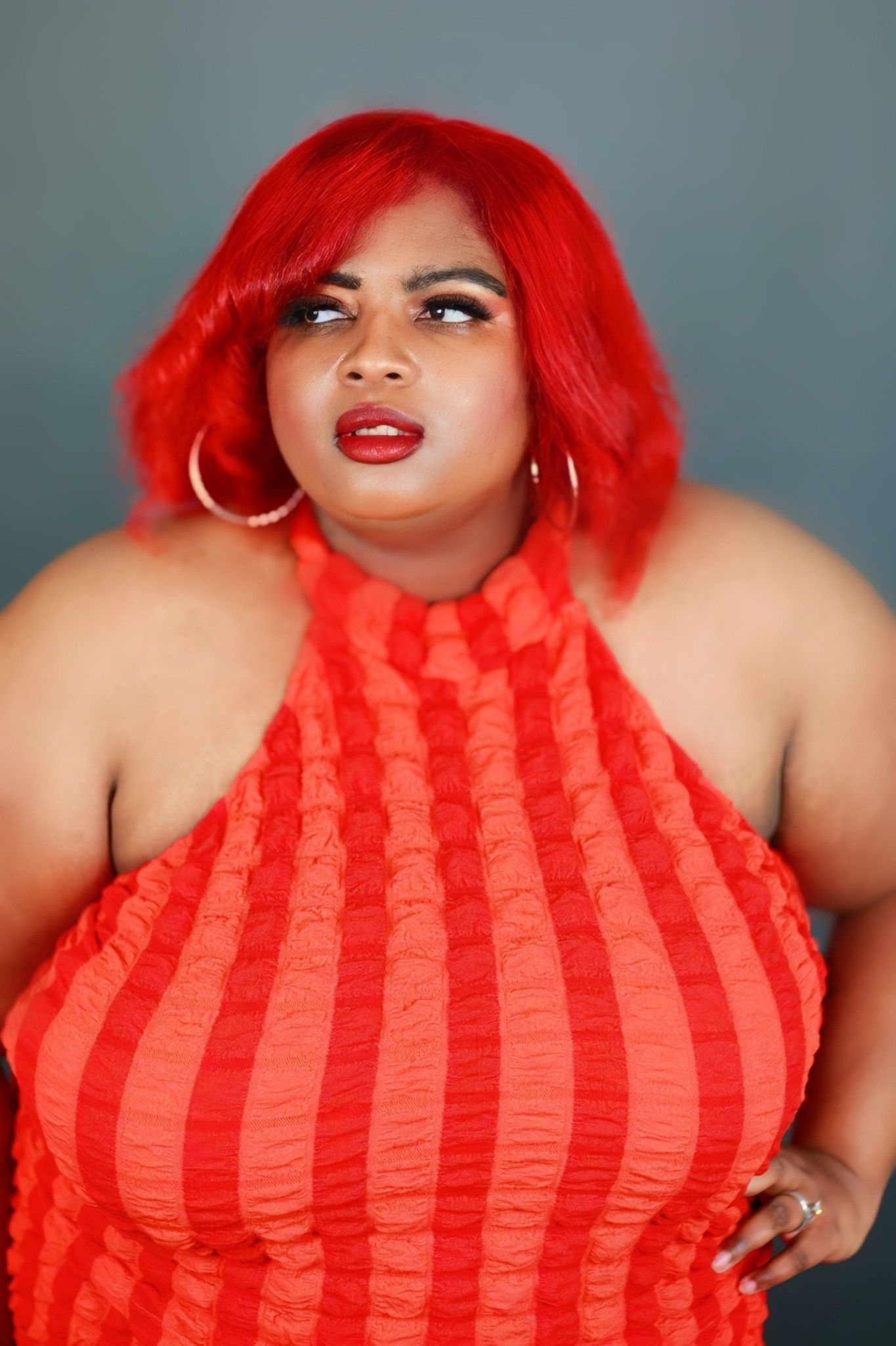 A woman with red hair is wearing a red halter top.