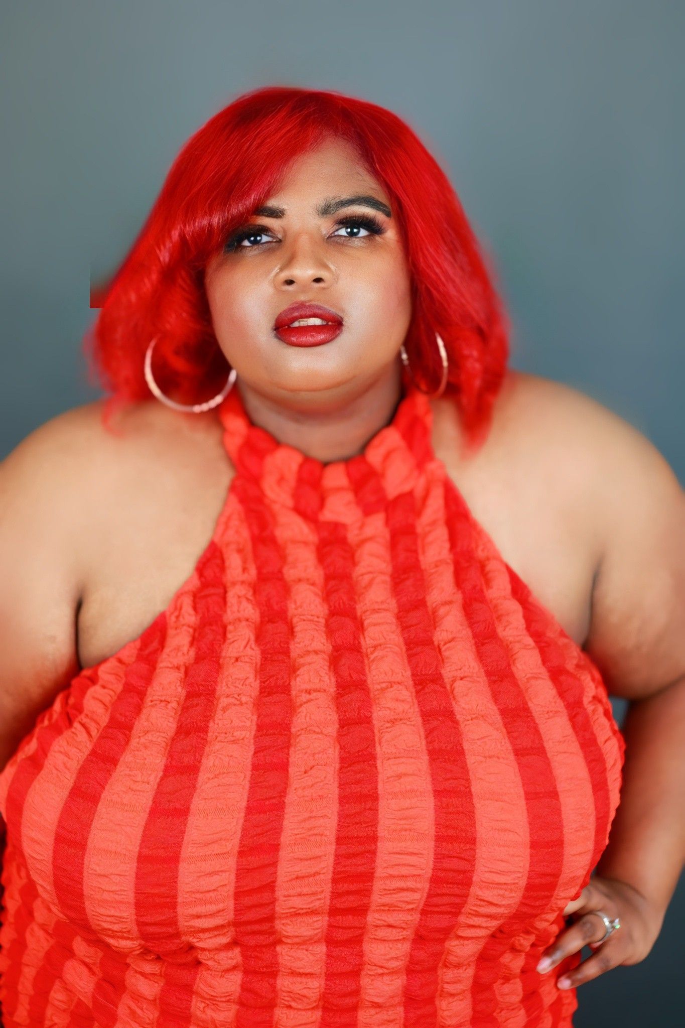 A woman with red hair is wearing a red striped halter top.