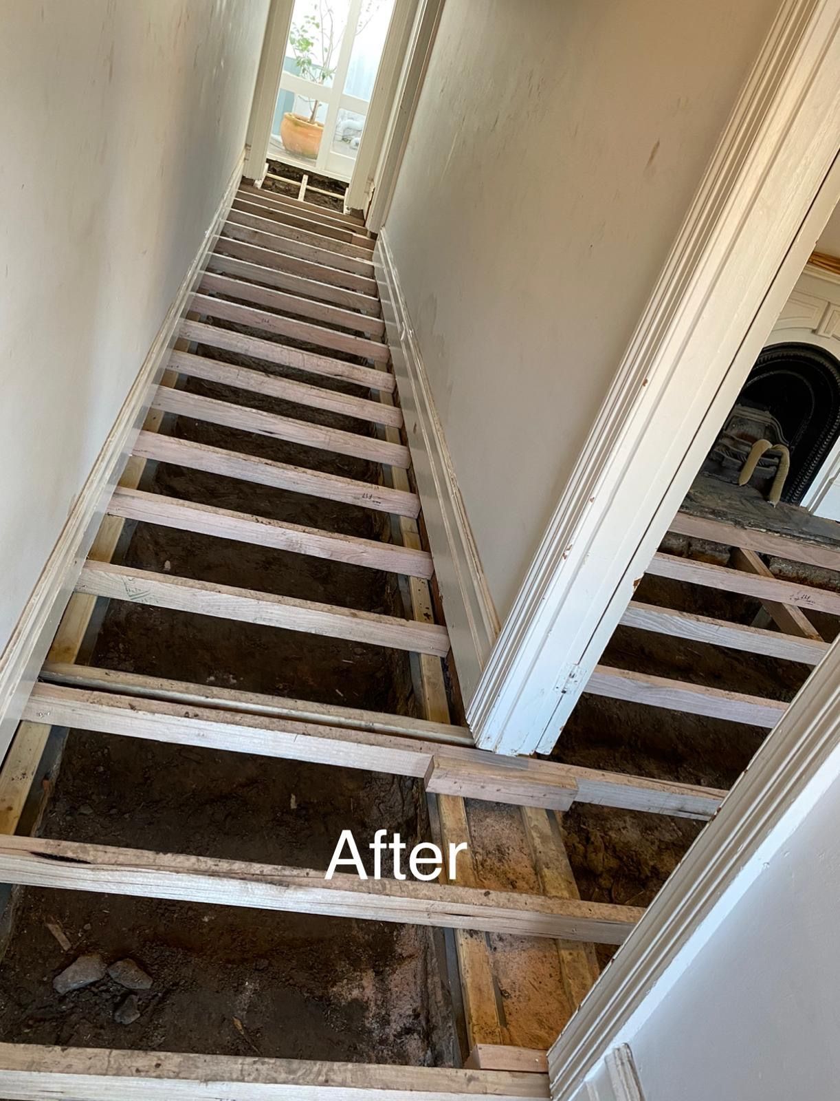 A picture of a hallway with a wooden floor and stairs.