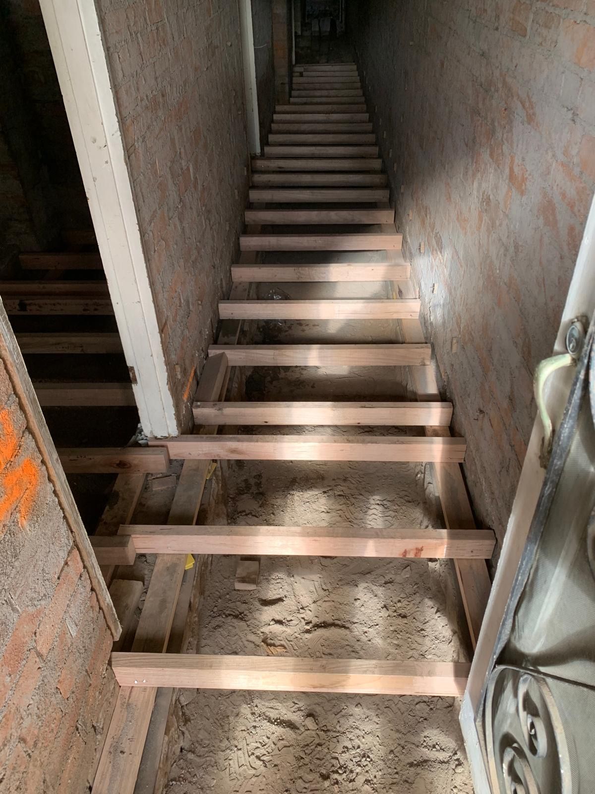 A wooden staircase is being built in a basement.