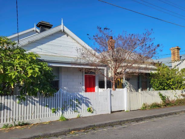 A white house with a red door and a white picket fence