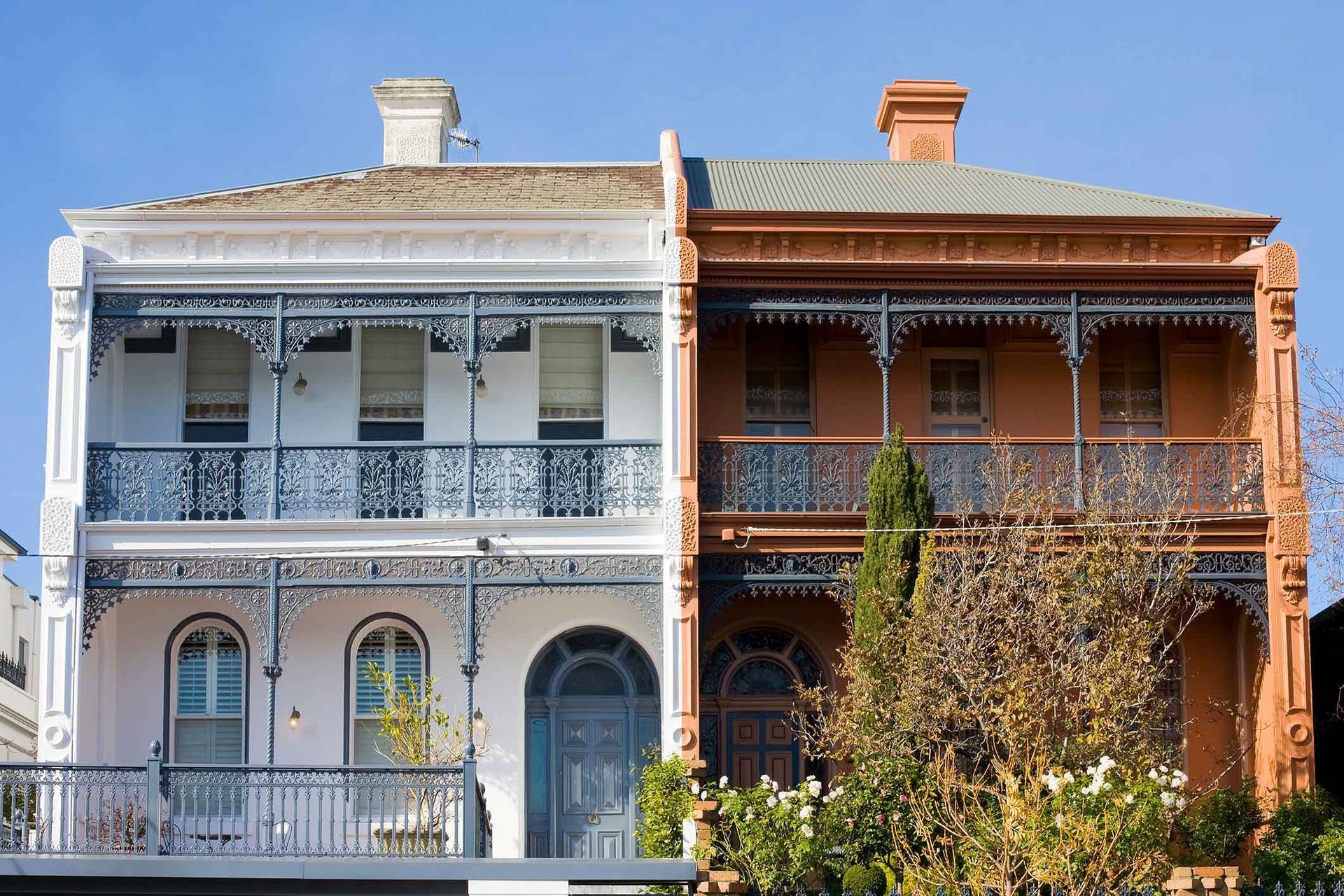 A white and orange building with balconies and a blue sky in the background