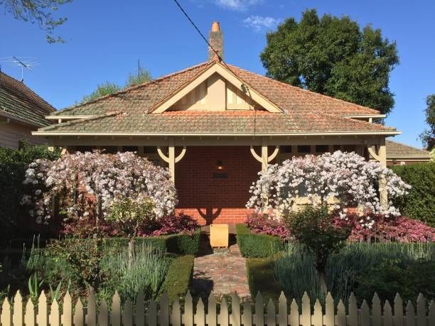 A house with a fence and flowers in front of it
