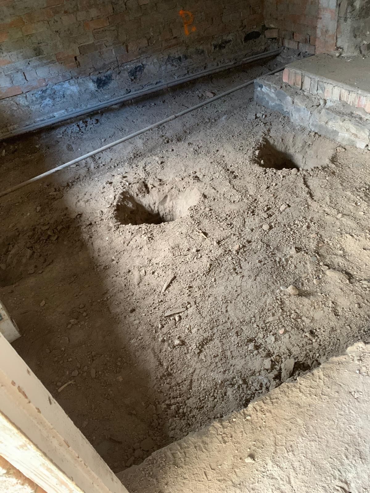 A room with a lot of dirt and a hole in the floor.