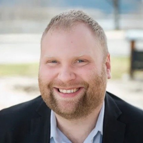 A man with a beard and a suit is smiling for the camera.