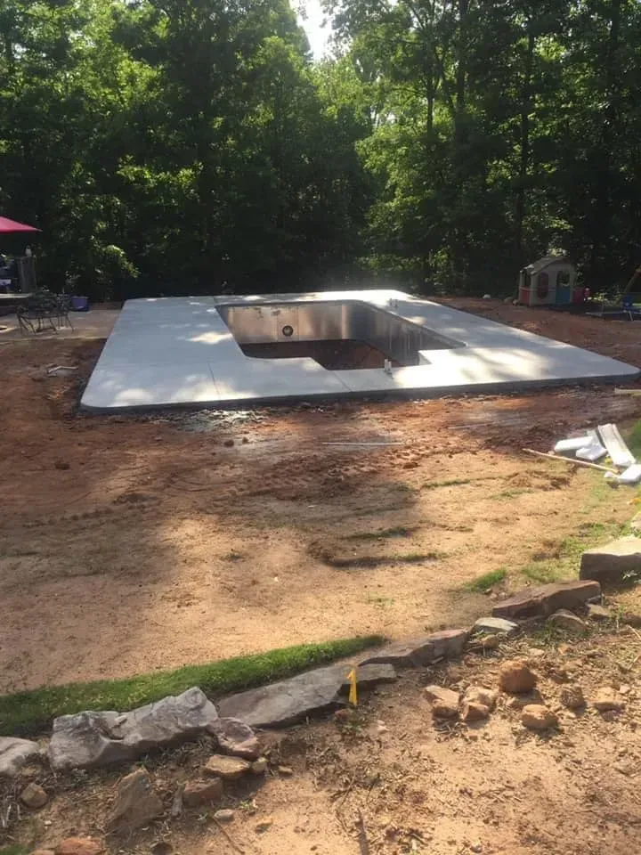 A swimming pool is being built in the backyard of a house.