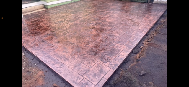 A man is working on a patio in front of a house.