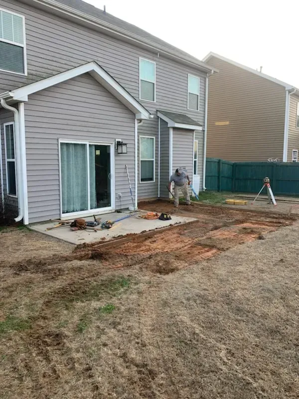 A man is working on a patio in front of a house.