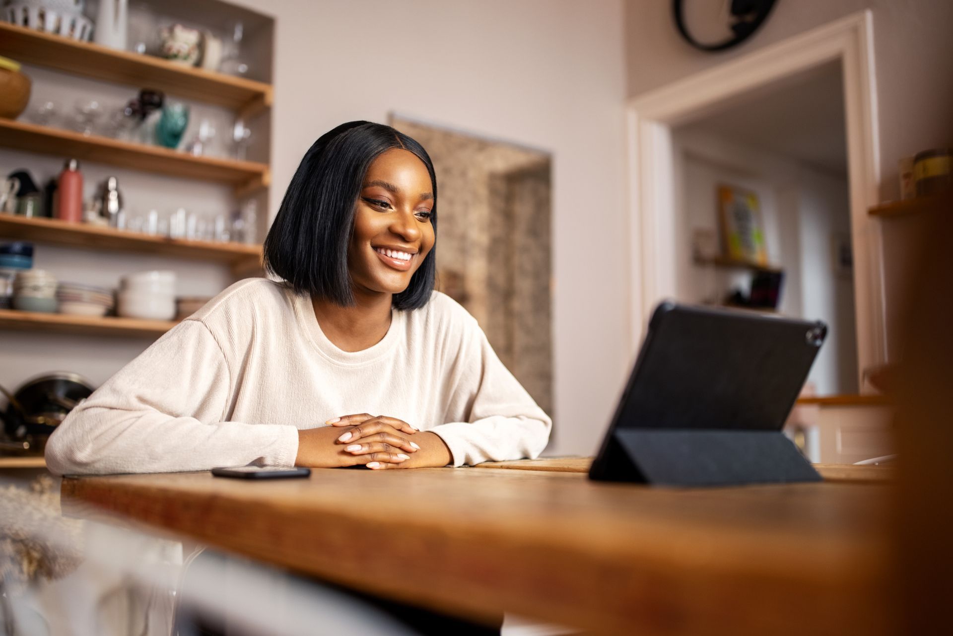 A woman is sitting at a table using a tablet computer.