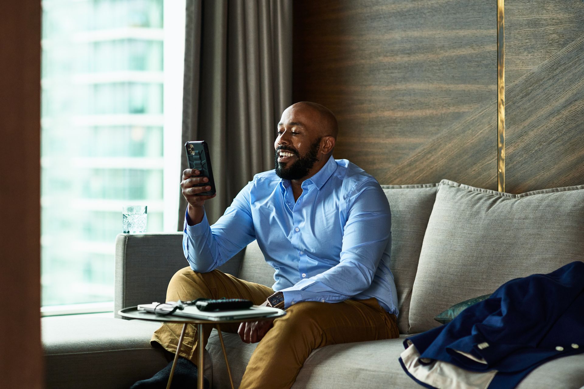 A man is sitting on a couch holding a cell phone.