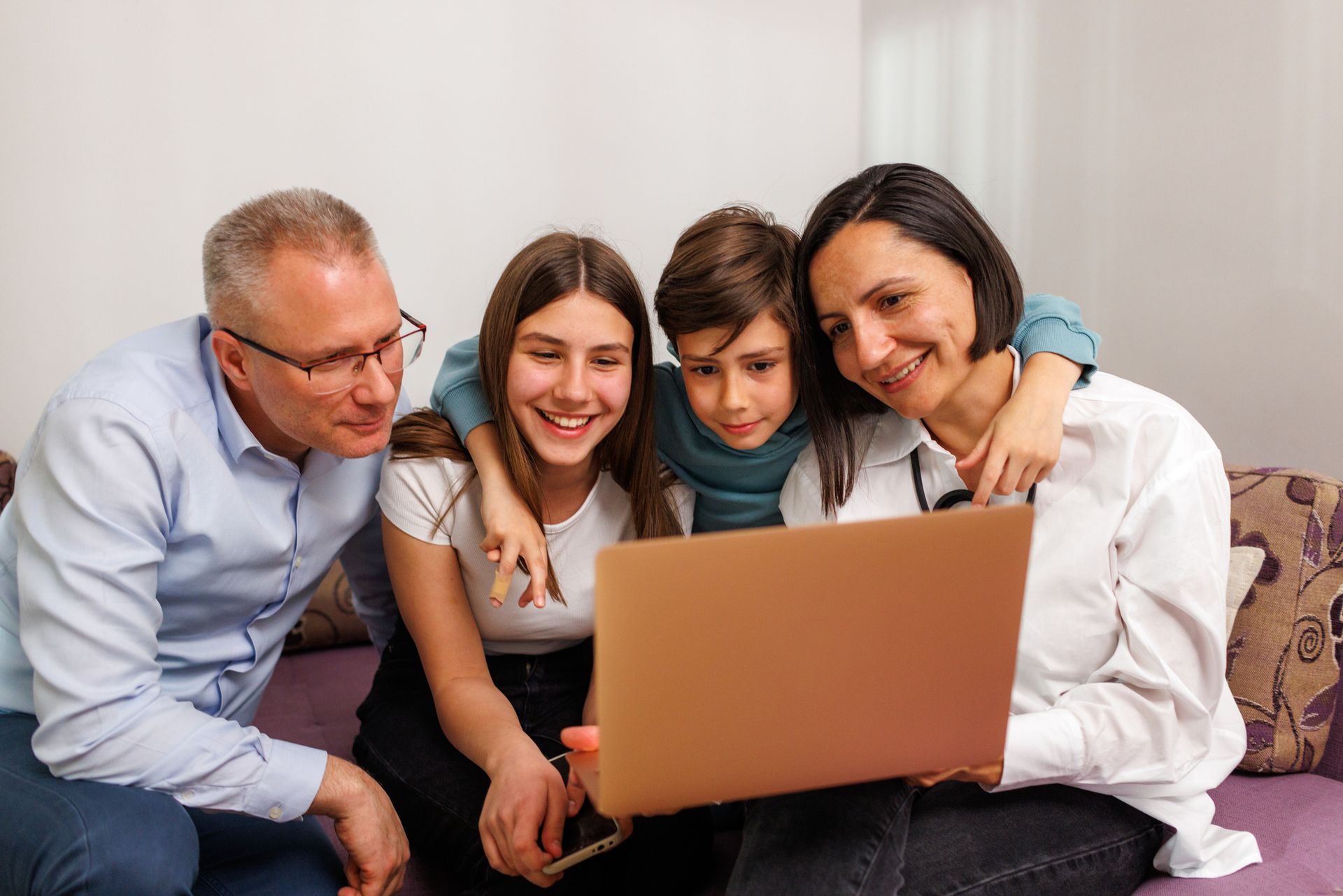 A family is sitting on a couch looking at a laptop computer.
