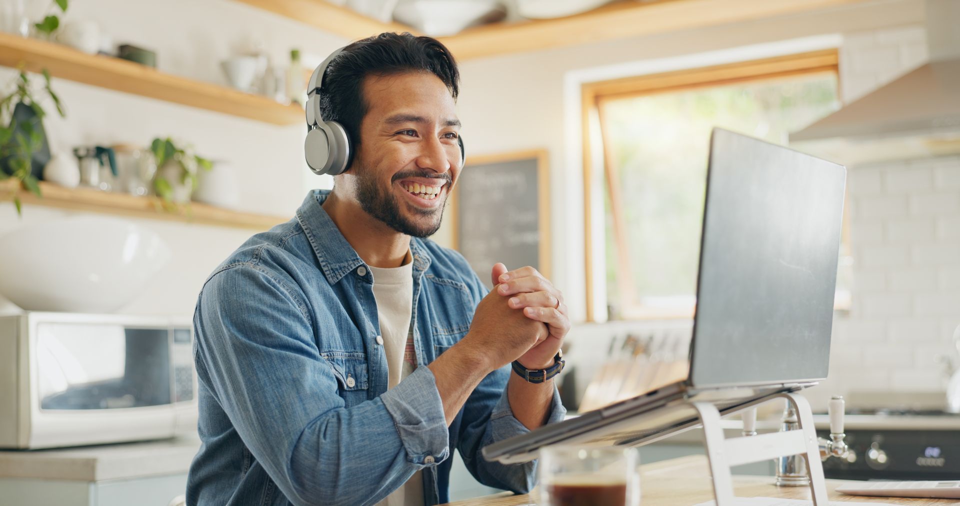 A man wearing headphones is sitting in front of a laptop computer.
