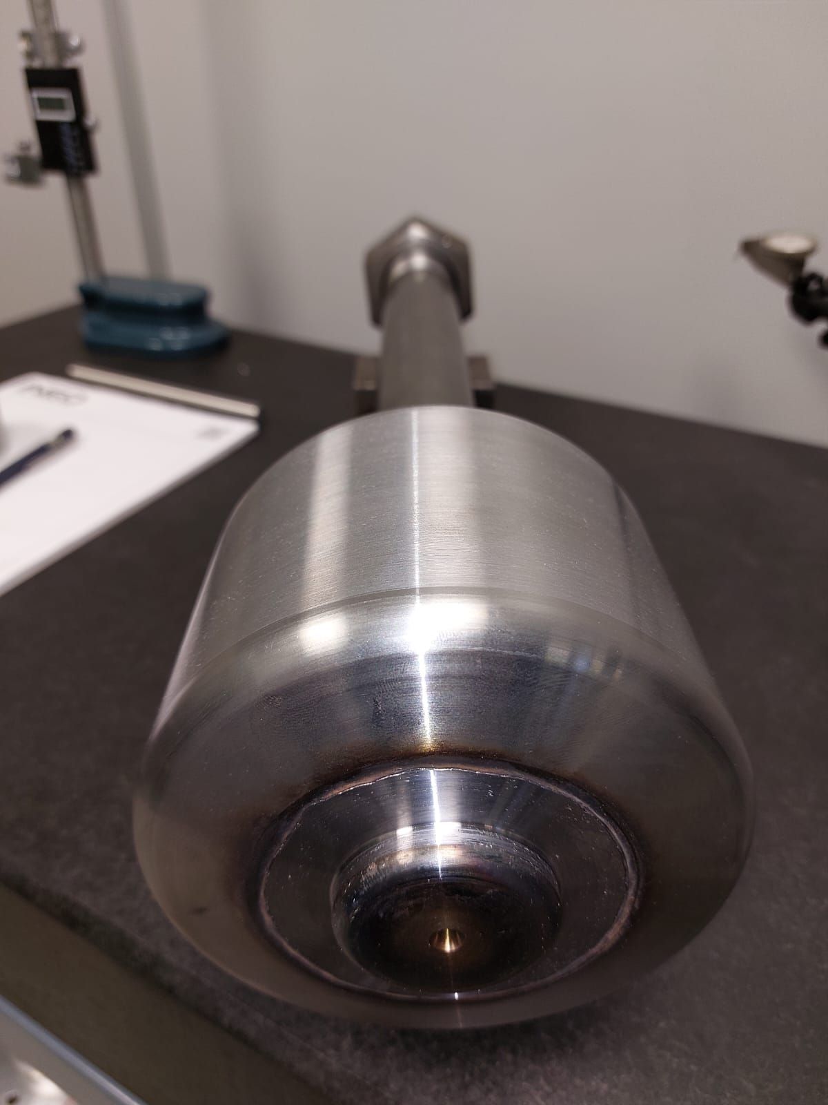 su un tavolo è posato un grande oggetto metallico