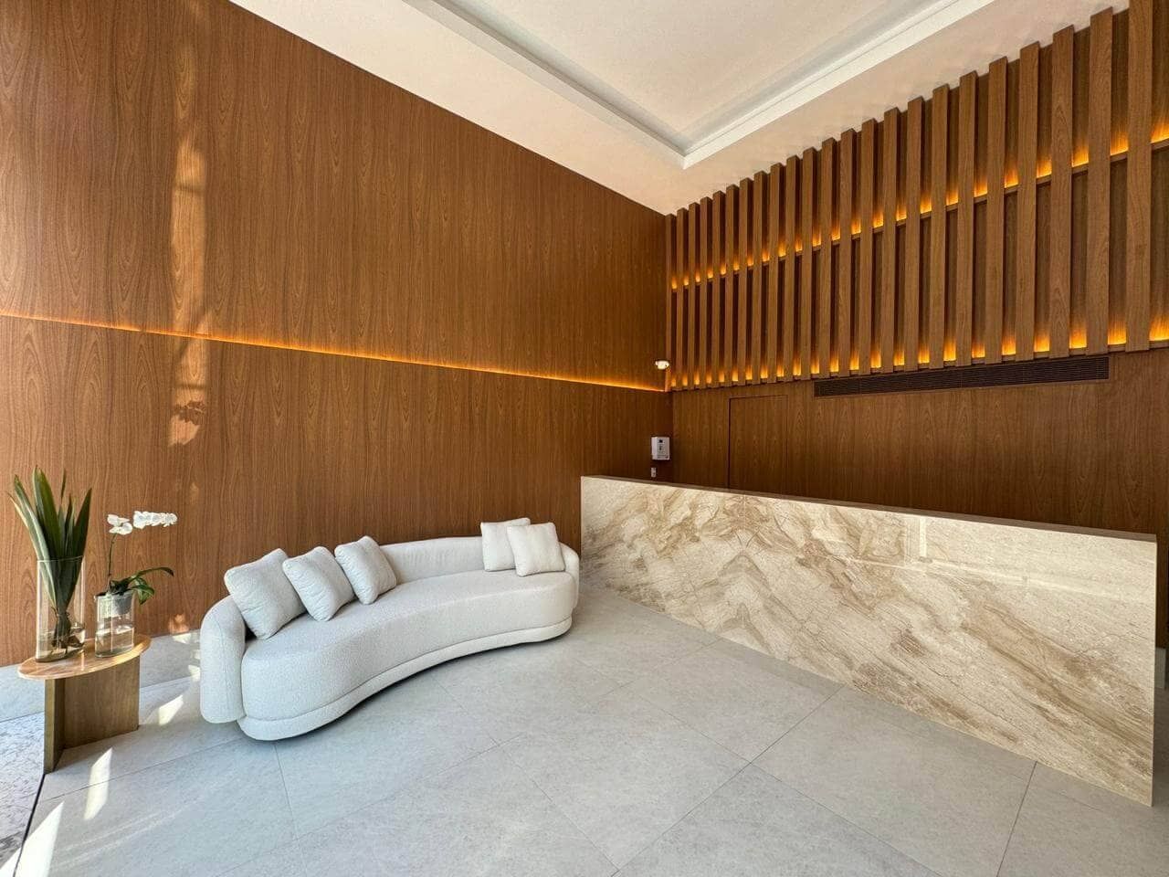 Um sofá branco está no saguão ao lado de um balcão de mármore.