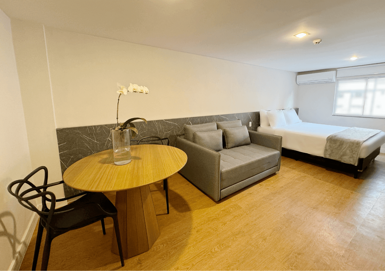 Um quarto de hotel com um sofá, mesa, cadeiras e uma cama.