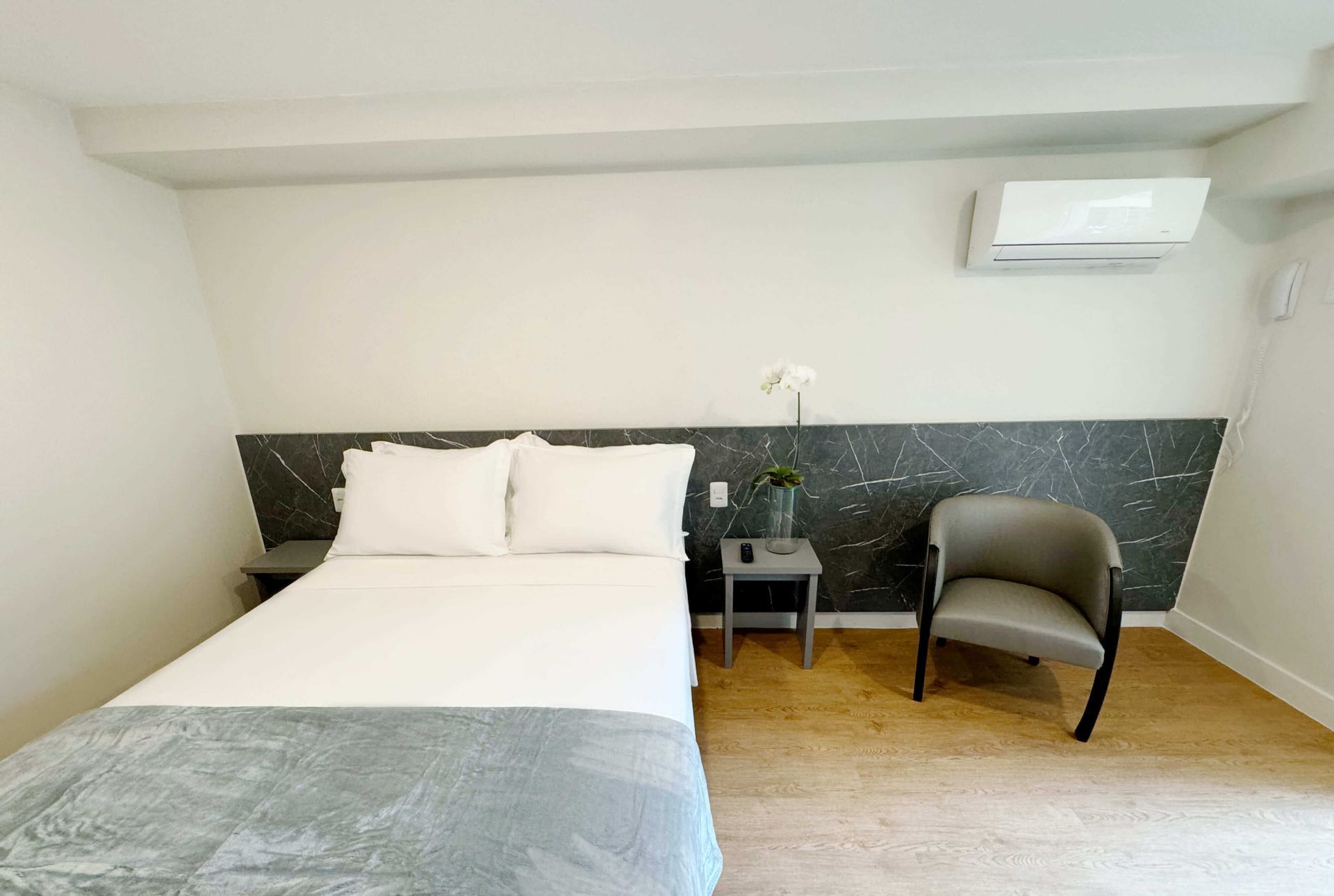 Há uma cama e uma cadeira no quarto.