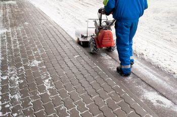 A Man Is Using a Snow Blower to Remove Snow from A Sidewalk | Dickinson, ND | Unleashed Contracting