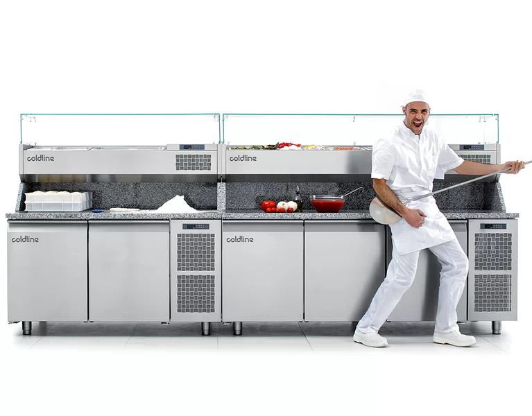 Uno chef è in piedi davanti al bancone della cucina e tiene in mano una spatola.