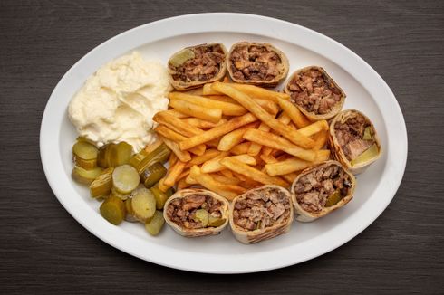 Arabi Beef Shawarma A white plate topped with french fries , pickles and garlic spread