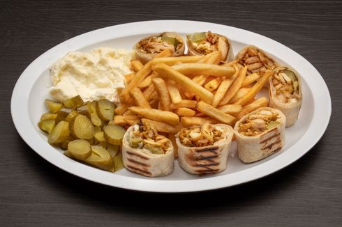 A plate of food with french fries and pickles on a table.