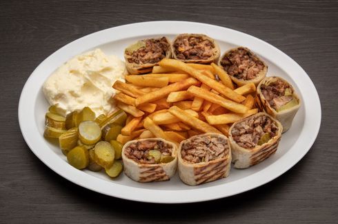 A plate of food with french fries and pickles on a table.